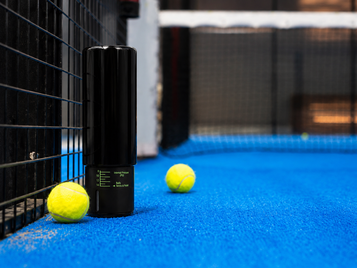 Balles de padel et pressurisateur sur un court bleu