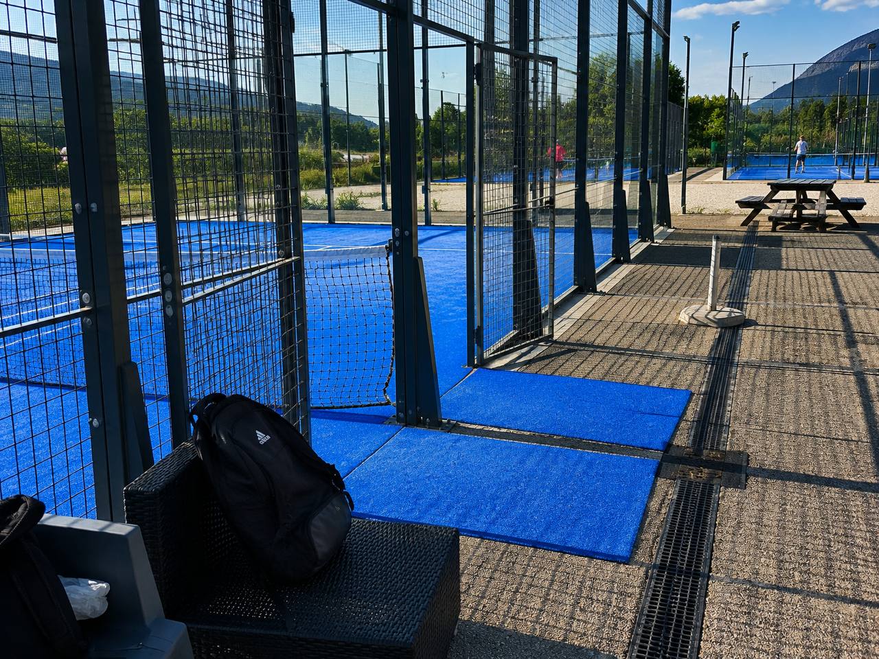 Sac de padel posé au bord d'un terrain de padel extérieur