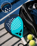Raquette de padel équipée de la protection LBS posée près d'un sac sur un court